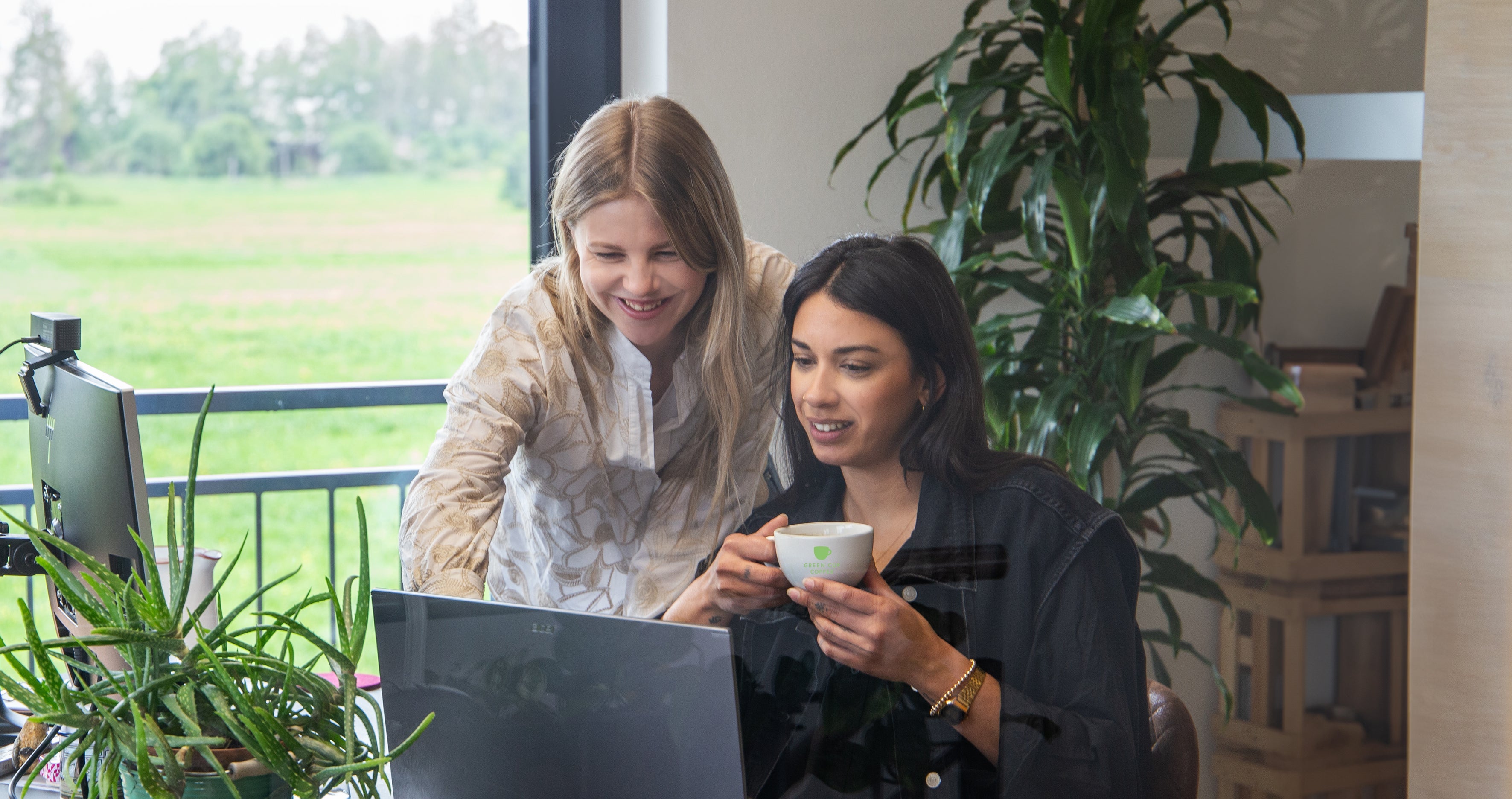 Zwei Kolleginnen im Büro trinken Kaffee und arbeiten