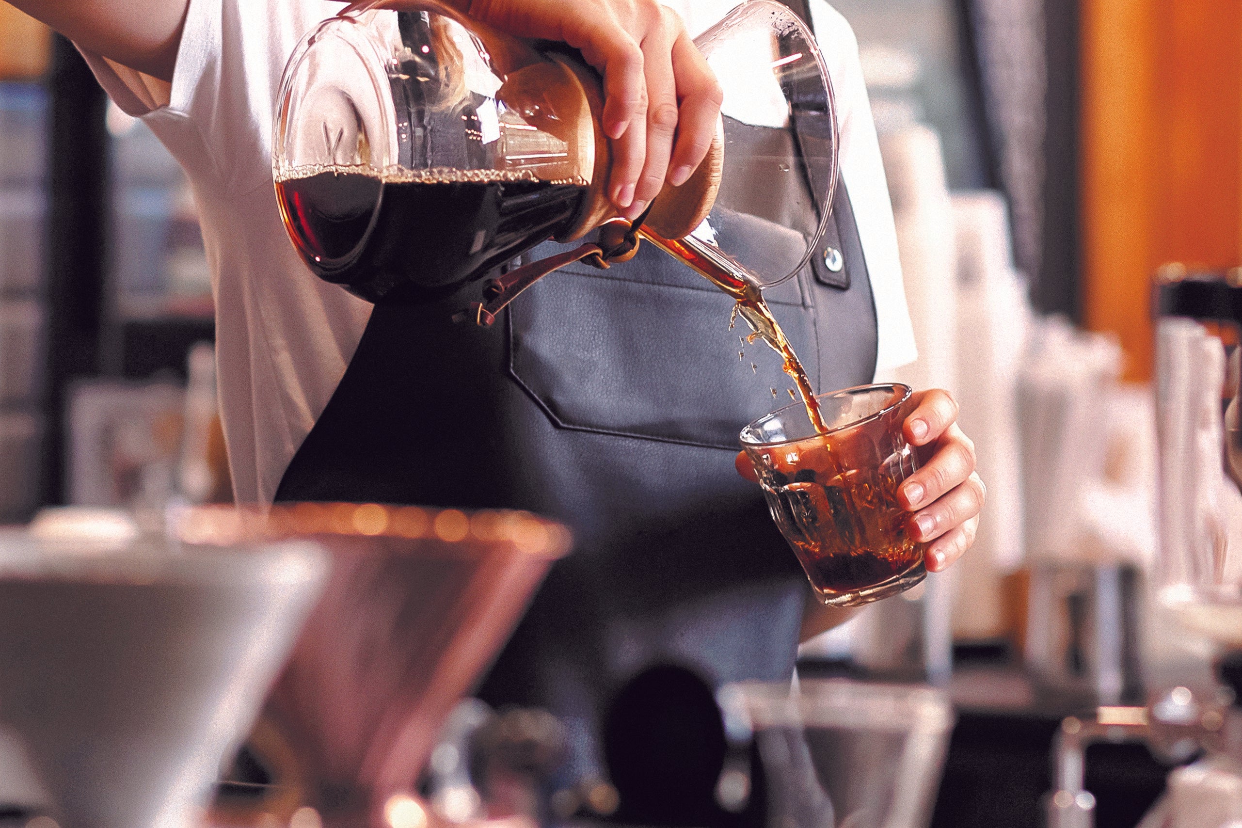 Barista schenkt Brühkaffee Filterkaffee zubereitet in einer Chemex in ein Glas einem Café