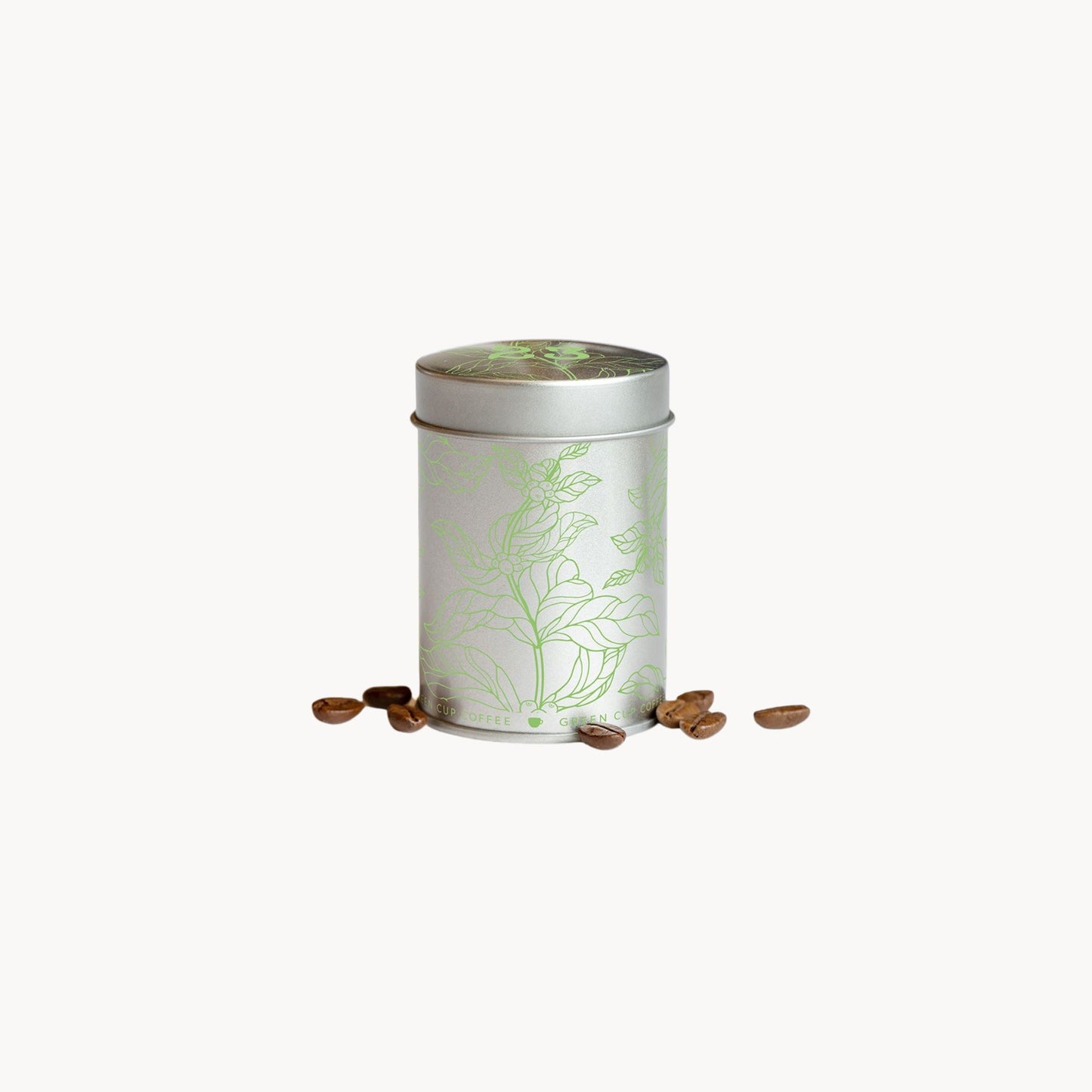 Silberne Kaffeedose von Green Cup Coffee mit grünem Pflanzenmotiv und Kaffeebohnen auf weißem Hintergrund