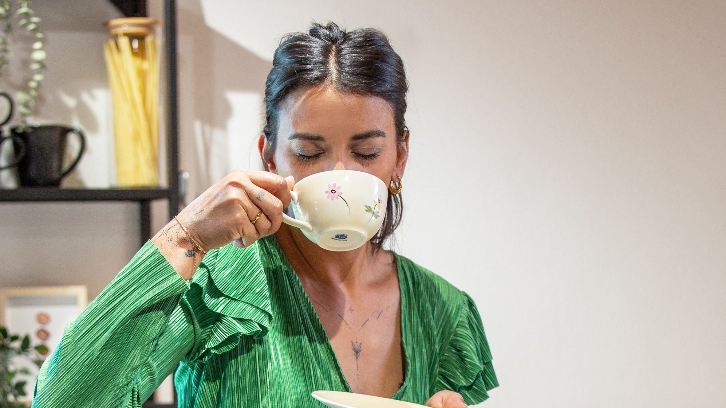 Frau sitzt in der Küche und genießt ihre Tasse Kaffee