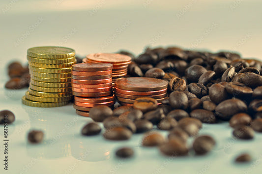 Stapel aus Euro-Münzen liegen zwischen gerösteten Kaffeebohnen – Symbolbild für den Zusammenhang von Kaffeepreis und Produktionskosten.