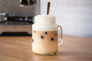 Iced Vanilla Latte im Glas mit Strohhalm und Löffel
