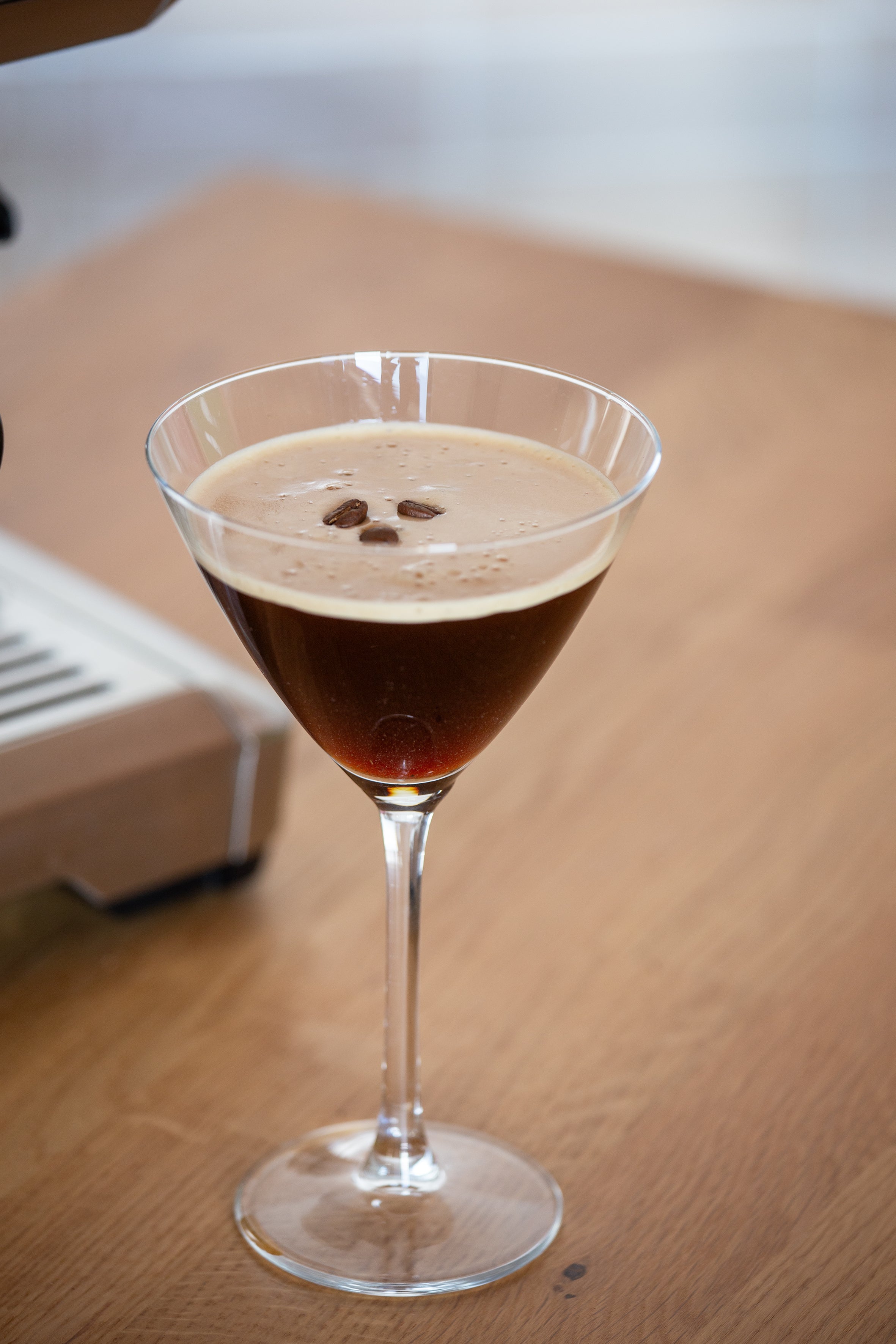 Espresso Martini Drink mit drei Kaffeebohnen auf Holztisch