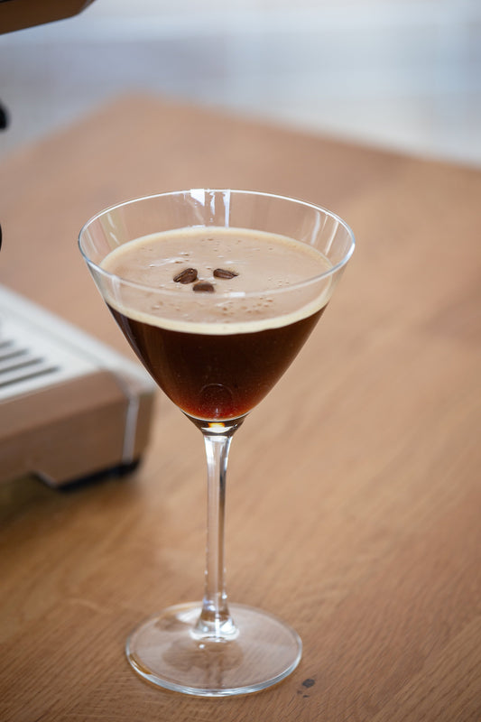 Espresso Martini Drink mit drei Kaffeebohnen auf Holztisch