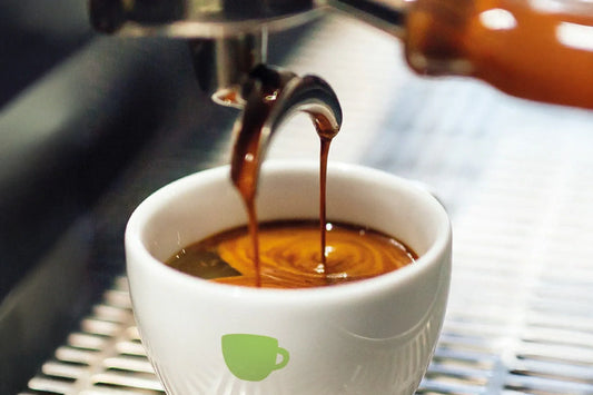 Frisch gebrühter Espresso läuft aus der Siebträgermaschine in eine weiße Tasse – mit dichter, goldbrauner Crema.