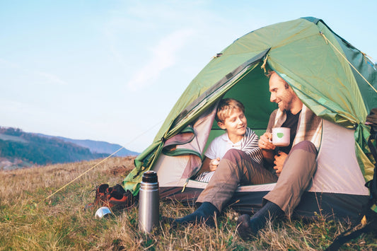 Outdoor Kaffee: Vater und Sohn sitzen im zelt, vater trintk eine tasse kaffee