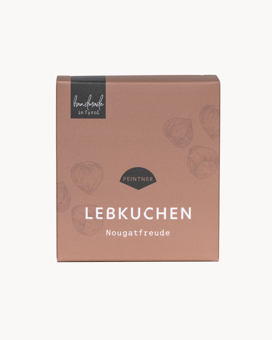 Lebkuchen: hellbraune Verpackung mit Haselnüssen Zeichnungen und der Aufschrift „Lebkuchen Nougatfreude“ von Peintner, handmade in Tyrol.