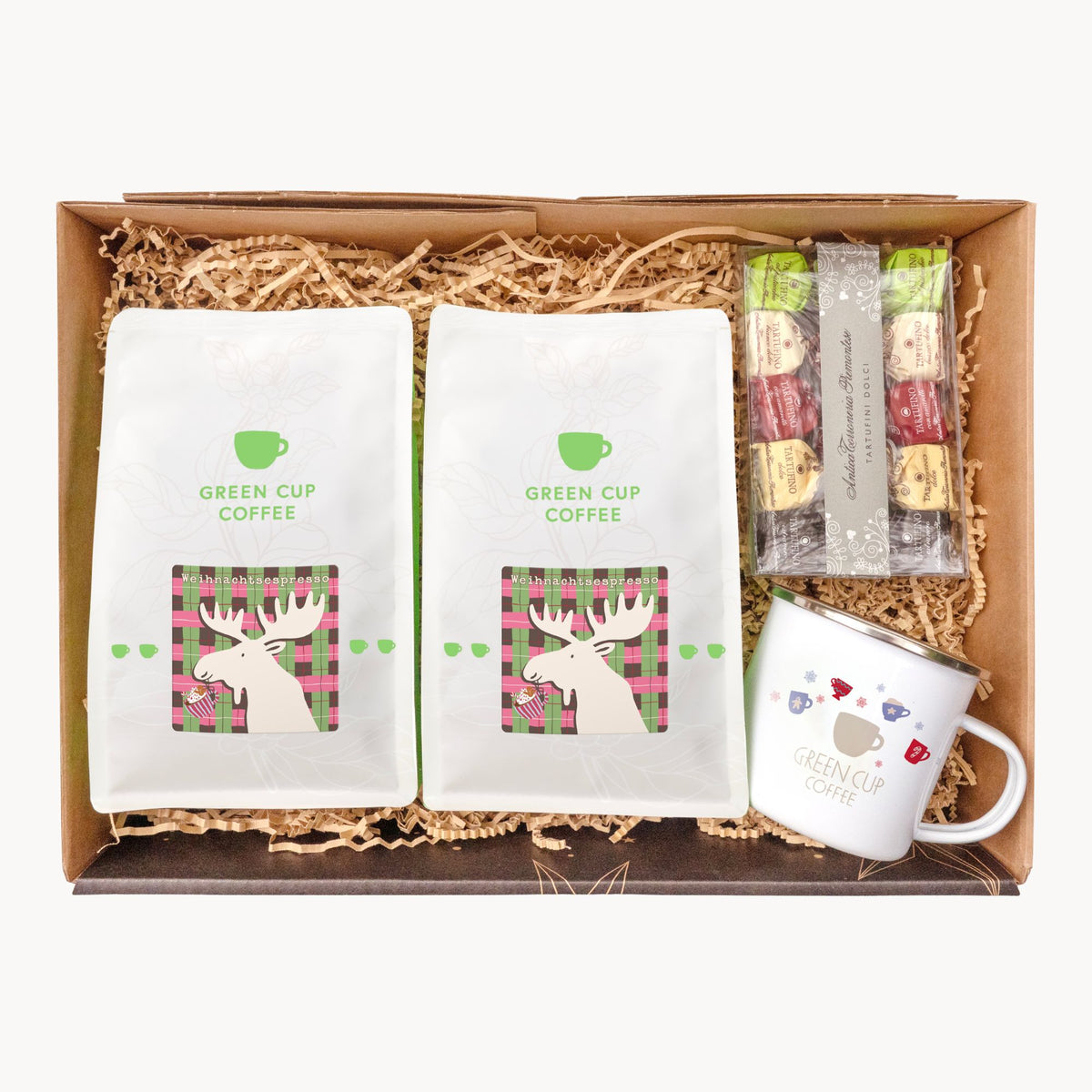 Geschenkbox mit zwei Tüten Weihnachtsespresso, einer Packung Tartufo-Trüffel und einer weißen Emailletasse mit Green Cup Coffee Logo.